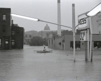 An emergency worker in a rowboat paddles out onto Cameron Street.